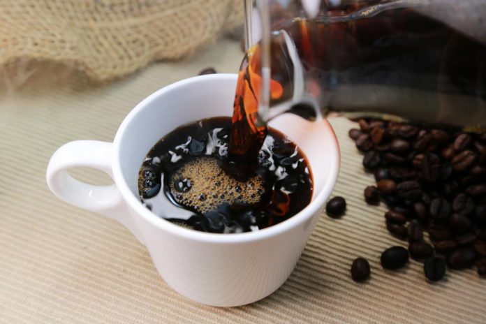 caffeine-in-coffee-being-poured-into-cup-surrounded-by-coffee-beans