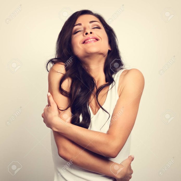 Happy sporty woman hugging herself with natural emotional enjoyi