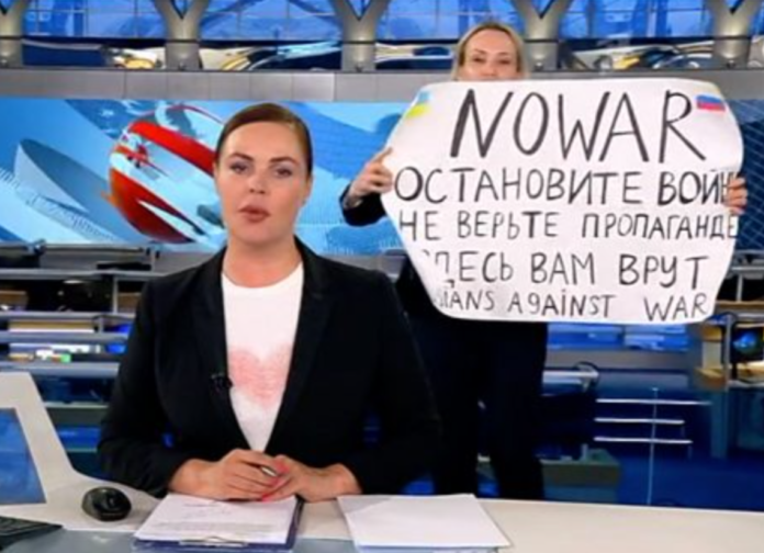 Woman holding an anti-war sign ran onto the set of a Russian evening news programme on the state-controlled Channel 1