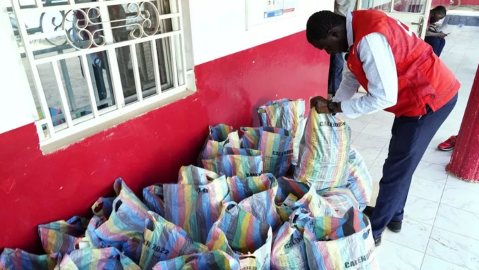 A member of the Gambian Red Cross looks through sacks of cough syrups that have been collected/ PC: Getty Images