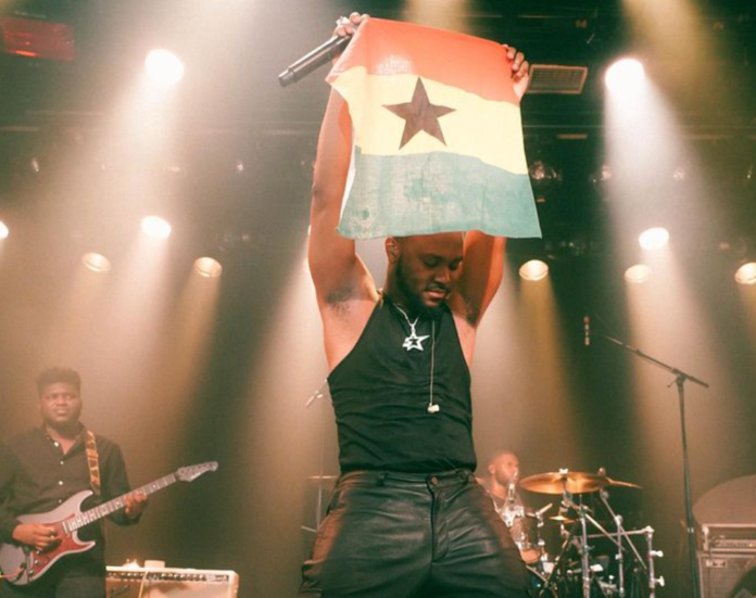 King Promise projects a Ghana flag during one of his 5 Star world tour performances in Europe King Promise projects a Ghana flag during one of his 5 Star world tour performances in Europe