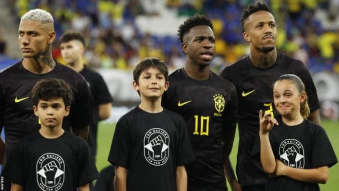 Vinicius Jr (centre) and his Brazil team-mates wore black kits for the first half of last month's friendly against Guinea while mascots wore t-shirts that read 'with racism there is no game' Vinicius Jr (centre) and his Brazil team-mates wore black kits for the first half of last month's friendly against Guinea while mascots wore t-shirts that read 'with racism there is no game'