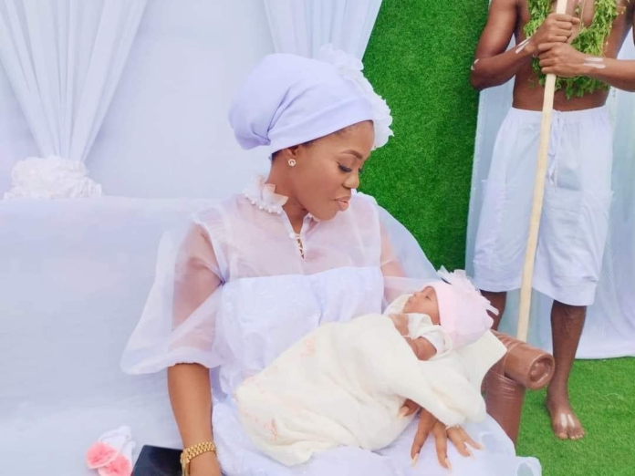 Mzbel shows daughter's face as she holds traditional outdooring ceremony