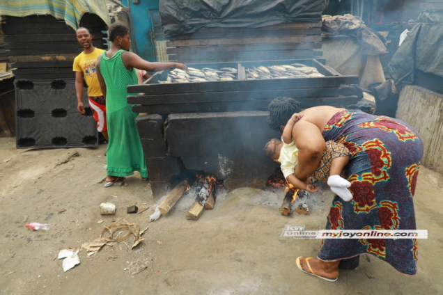 Naa Koshie, a fishmonger at Chorkor exposes her baby to heat and smoke when she tried to put fire woods into the oven. Photo by David Andoh