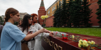 EPA/ People lay flowers as tribute to the victims of Sunday's attack on a memorial bearing the word Sevastopol in Moscow