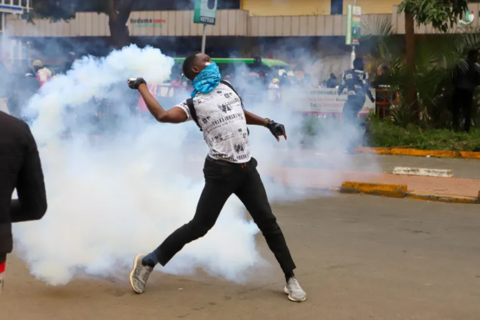 A protester throws a tear gas canister back at police officers during a protest over proposed tax hikes in Nairobi, Kenya on June 20, 2024 [Andrew Kasuku/AP]