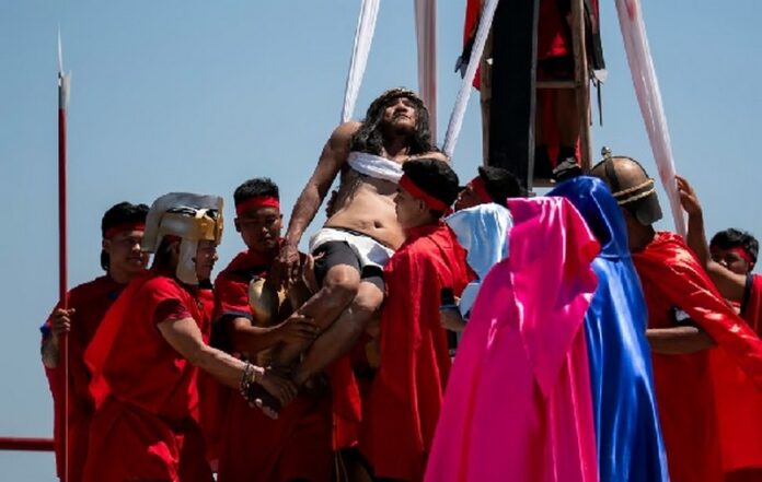 Ruben Enaje is carried after being nailed to the cross during his reenactment of the crucifixion of Jesus Christ on Friday