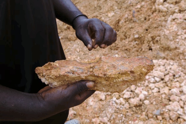 An illegal artisanal miner inspects an excavated rock for traces of gold at the Prestea-Huni Valley Municipal District in the Western Region, Ghana August 17, 2024. REUTERS/Francis Kokoroko